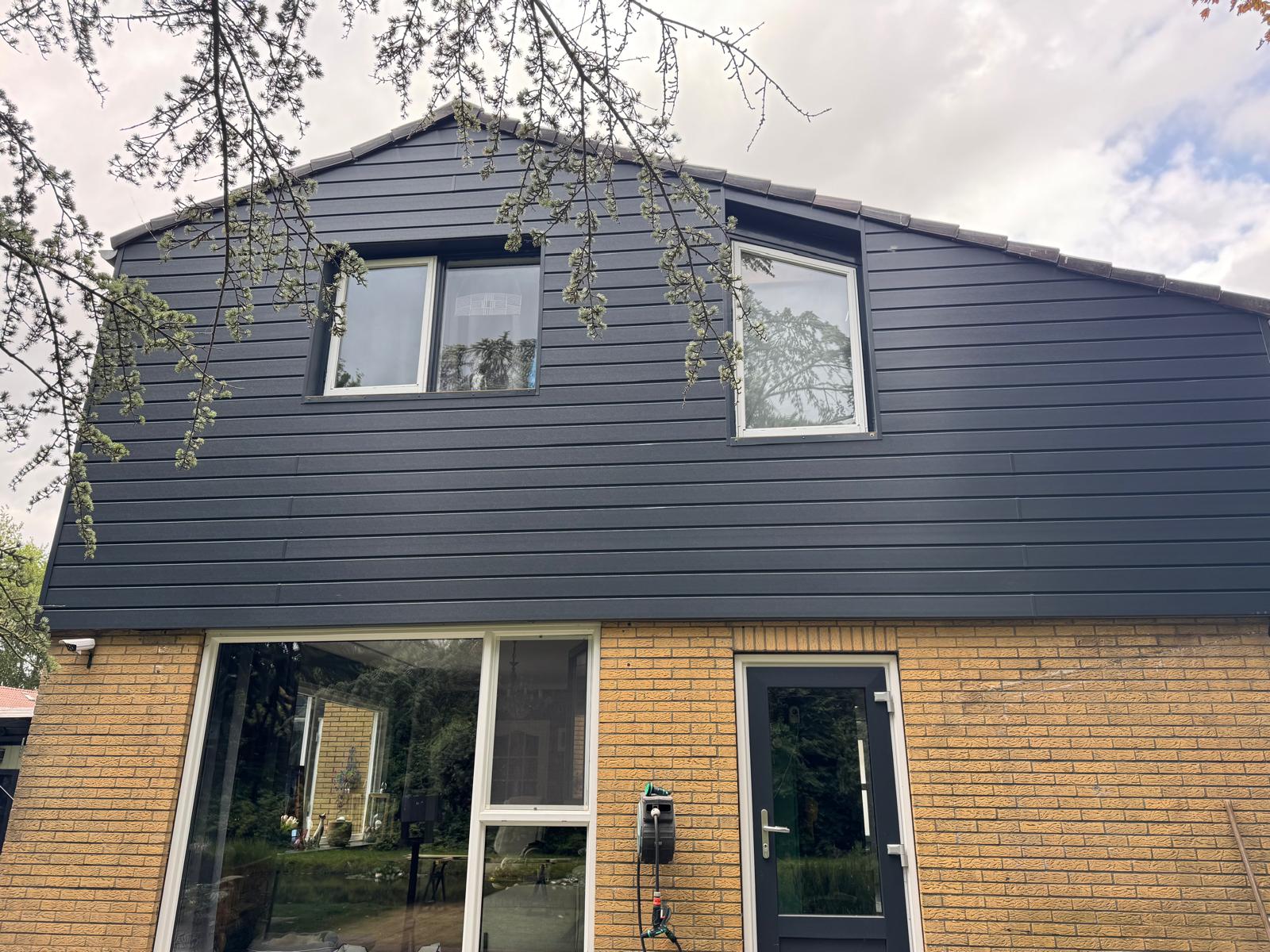 Gevel met donkere Keralit gevelbekleding naast bestaand metselwerk